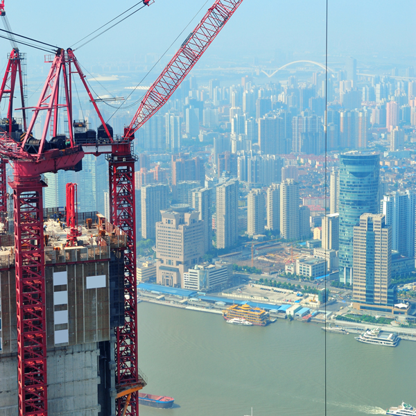 A crane operates on a building site, surrounded by scaffolding, showcasing construction progress and activity.