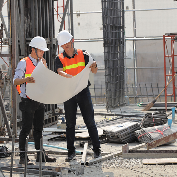 Two men in hard hats standing on a construction site.